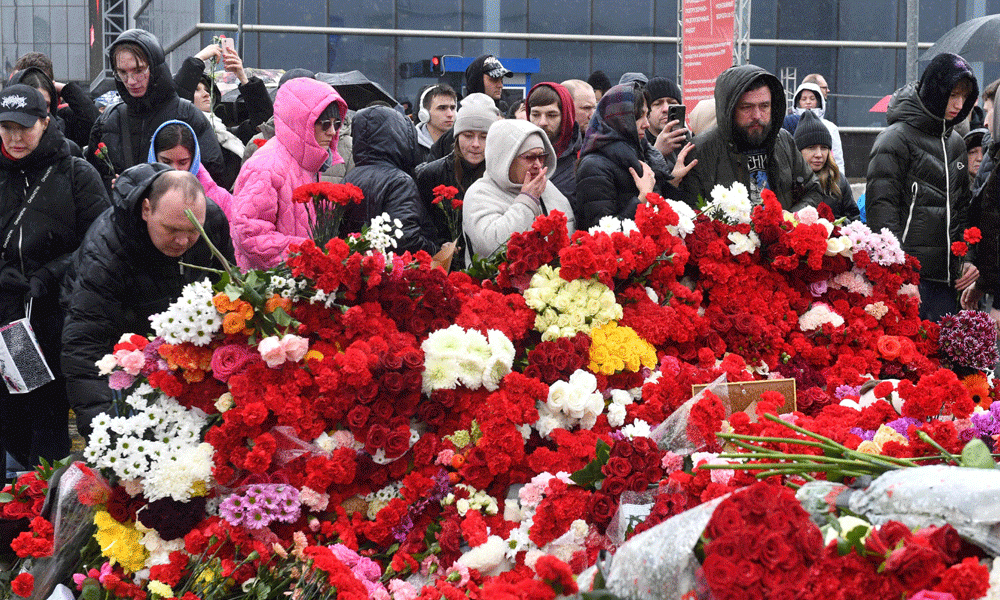 People lay flowers at a makeshift memorial in front of the Crocus City Hall in Krasnogorsk on March 24, 2024, as Russia observes a national day of mourning after a massacre that killed more than 130 people. Photo : AFP