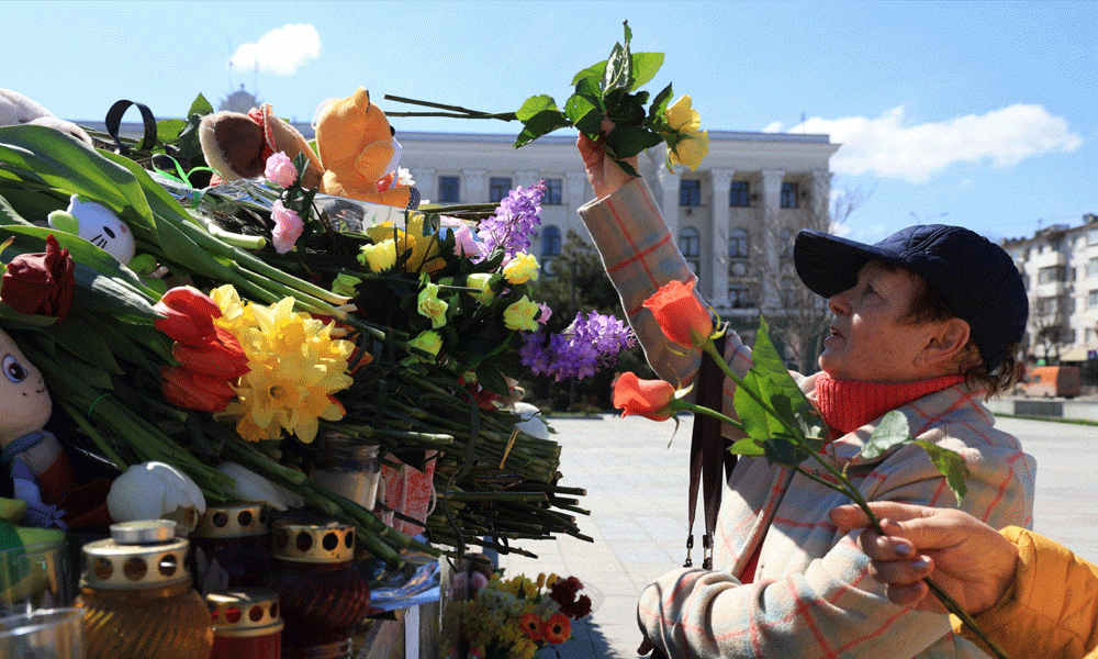 A woman lays flowers at a makeshift memorial in Simferopol, Crimea, on March 24, 2024, as Russia observes a national day of mourning after a massacre in the Crocus City Hall that killed more than 130 people, the deadliest attack in Europe to have been claimed by the Islamic State (IS) group. Photo : AFP