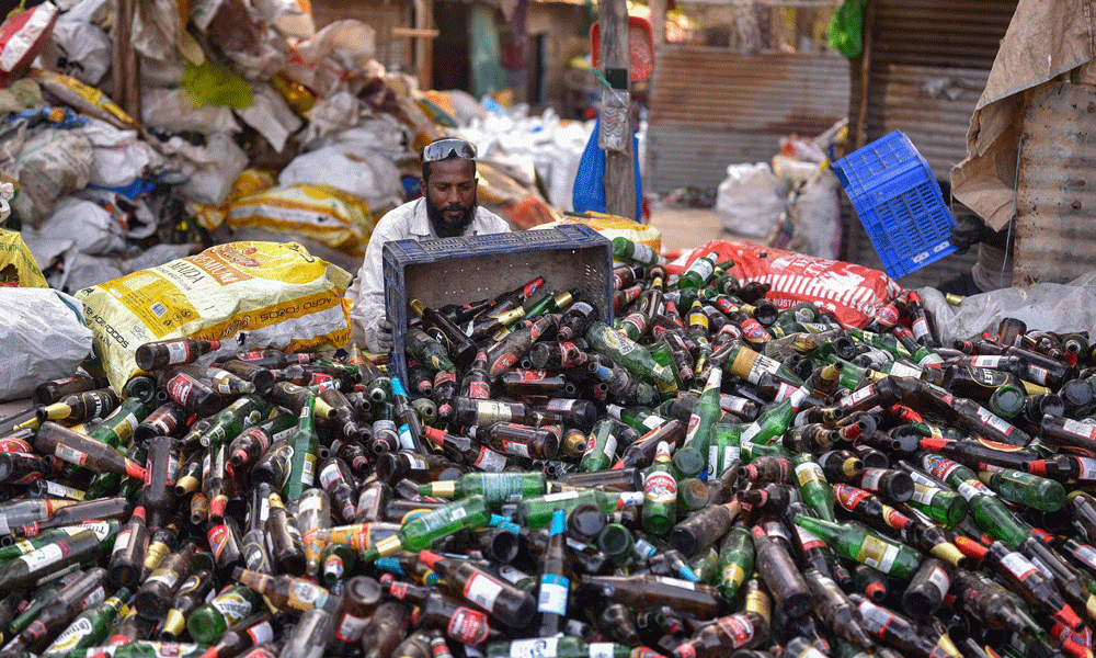 In this photograph taken on January 29, 2024, a worker collects empty beer bottles for recycling at a unit in Bengaluru. Photo : AFP